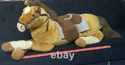 Cheval de peluche géant avec selle assis sur un coussin en peluche animal brun