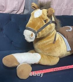 Cheval de peluche géant avec selle assis sur un coussin en peluche animal brun