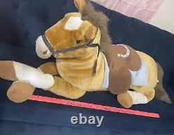 Cheval de peluche géant avec selle assis sur un coussin en peluche animal brun